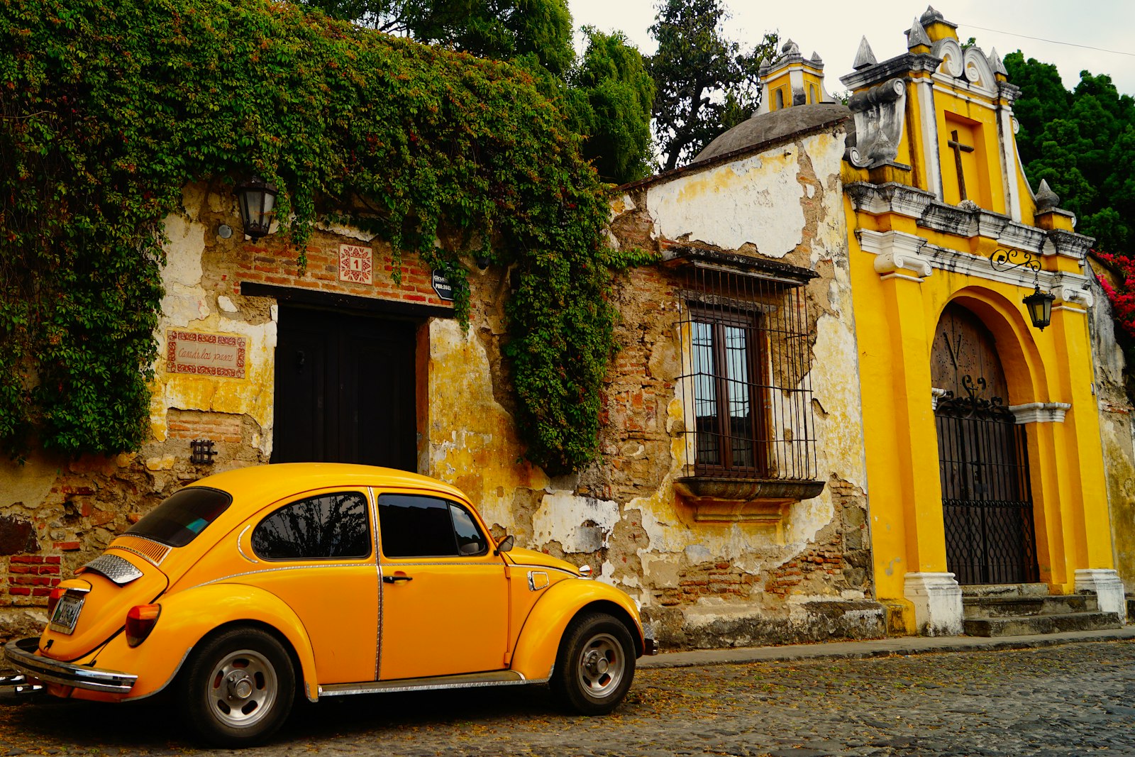 A yellow vintage Volkswagen Beetle parked in front of an old building